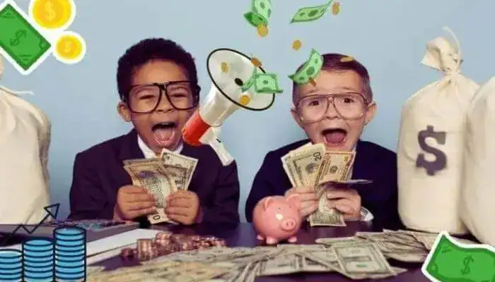 Two excited young boys in business suits sit at a desk covered in cash, illustrating the fun of learning how to make money as a kid